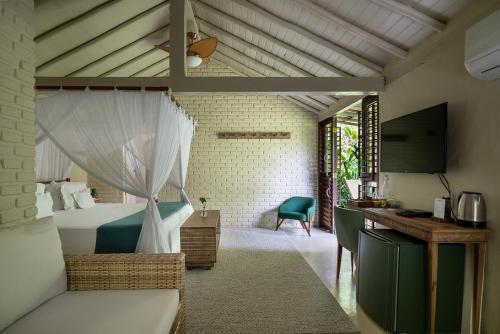 a bedroom with a bed and a desk and a television at Pousada Capim Santo in Trancoso