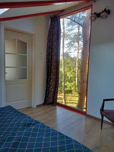 a bedroom with a large window with a view of a tree at ZegZug apartman in Pankasz