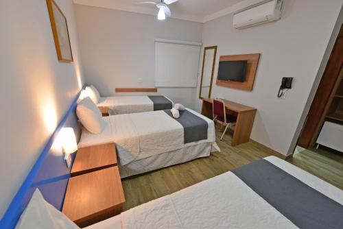 a hotel room with two beds and a television at Vinds Economic Hotel in Ipatinga