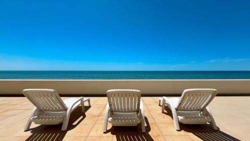 three chairs sitting on a balcony overlooking the ocean at Beautiful Huge Beachfront Home Serenity Beach in Puerto Peñasco