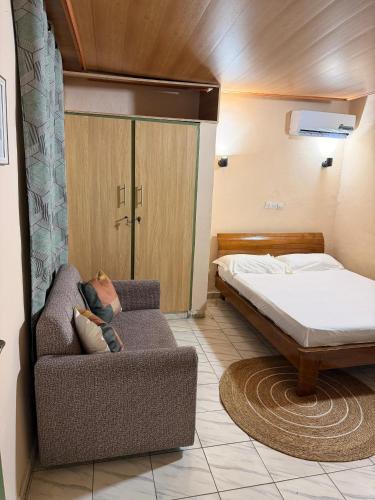 a bedroom with a bed and a couch and a bed at Studio spacieux Aéroport FHB in Abidjan