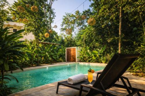 a villa with a swimming pool and a chair at Yaakun in Bacalar