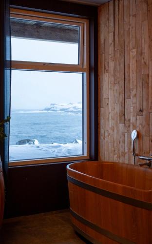 a bath tub in a room with a large window at Blabjorg Resort in Borgarfjörður Eystri