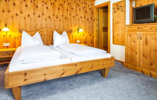 a bedroom with a large wooden bed with a television at Reitbauernhof in Grossarl