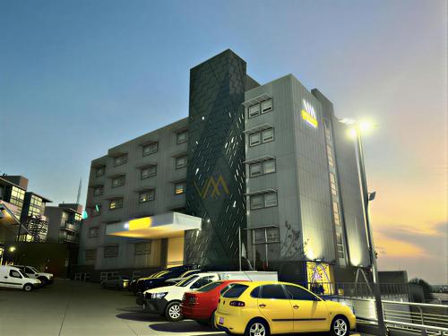 a parking lot with cars parked in front of a building at Hotel VM Express Queretaro in Mendiola