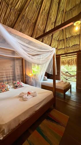 a bedroom with two beds in a straw hut at Finca Flor de Maria in El Zaino