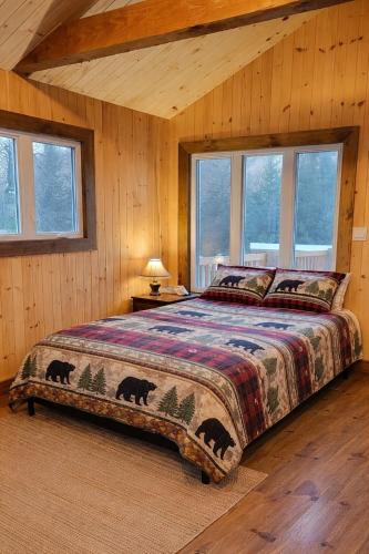 a bedroom with a bed in a room with windows at Le Chaleureux, Picanoc River in Kazabazua