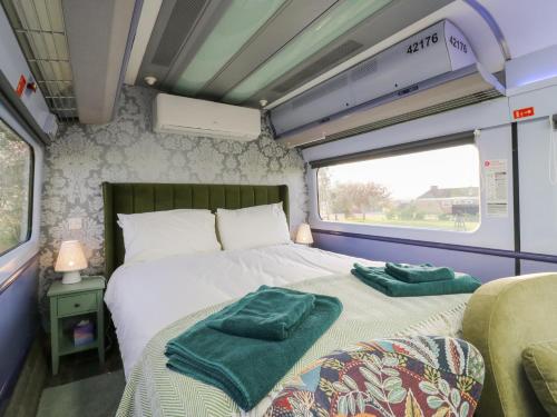 a bedroom with a bed with two green towels on it at The Carriage Ely Penzance in Ely