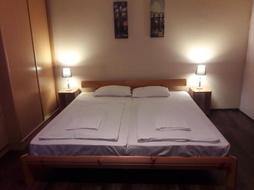ein Schlafzimmer mit einem Bett mit zwei Lampen auf beiden Seiten in der Unterkunft Home Apartman in Debrecen