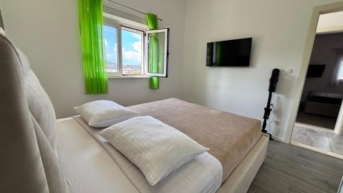 a bedroom with a bed with green curtains and a television at Apartment Stella in Ražanj