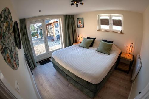 a bedroom with a large bed and a window at B&B Oud-Zilven Het Vogelhuisje in Loenen