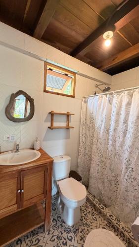 a bathroom with a toilet and a sink and a shower curtain at Finca Flor de Maria in El Zaino