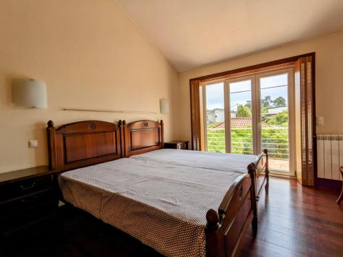 a bedroom with a wooden bed with a large window at Casa de Maria in Cotovia