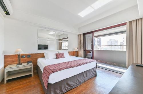 a bedroom with a large bed and a large window at Hotel Golden Park Campinas Cambuí By Nacional Inn in Campinas
