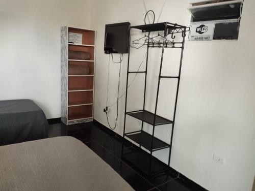 a room with a bed and a tv and a shelf at Espaço Ideal 4 in Cascavel