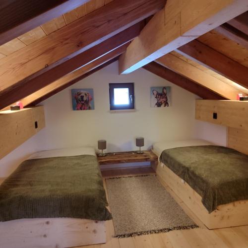 two beds in a room with wooden ceilings at Ferienhaus Träglhof in Hirschau