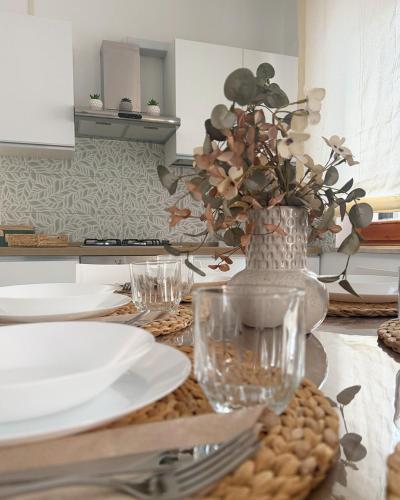 a table with plates and a vase with flowers in it at Cordi Casa Vacanze in Giulianova