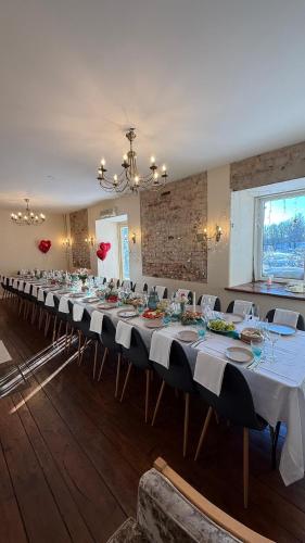 a long table with white tables and chairs in a room at Gaiziņstars in Bērzaune