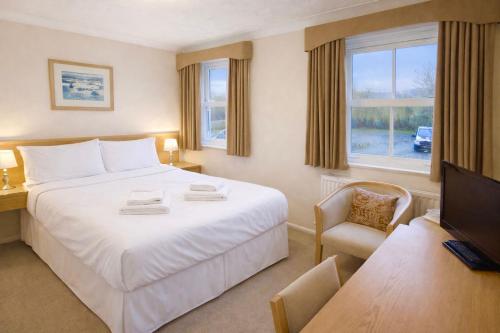a hotel room with a large white bed and a chair at The Inn at Emmington in Chinnor