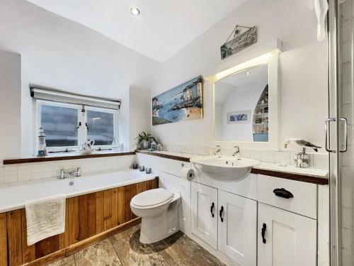 a bathroom with a sink and a toilet and a tub and a sink at Captains Cottage Minehead in Minehead