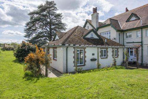 a large white house with a grassy yard at The Bramleys Old Cleeve in Washford