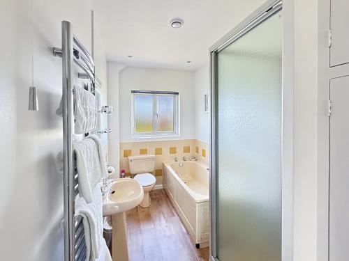 a bathroom with a tub and a sink and a toilet at The Bramleys Old Cleeve in Washford