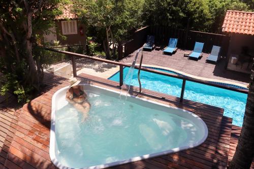 a woman in a bath tub next to a swimming pool at Calador Búzios Hotel in Búzios