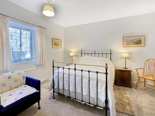 a bedroom with a bed and a chair and a window at Barn Cottage Brayford in Charles