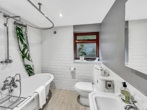a bathroom with a tub and a toilet and a sink at One Grooms Cottage Dunster in Dunster