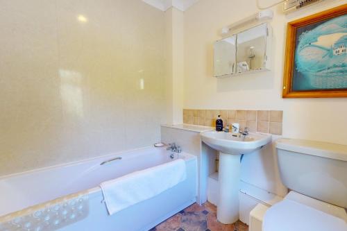 a bathroom with a tub and a sink and a toilet at Hillway Lodge Withypool in Withypool