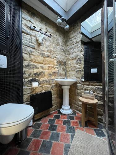 a stone bathroom with a toilet and a sink at Het Kathedraalhuis Goudblomme in Antwerp