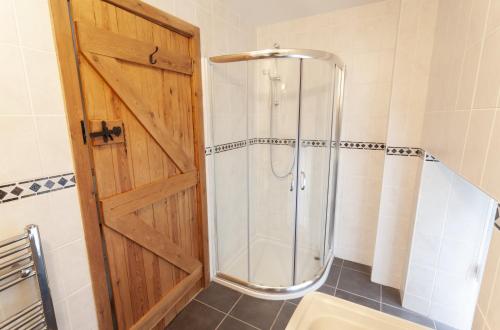 a shower with a wooden door in a bathroom at The Mill House Bampton in Bampton