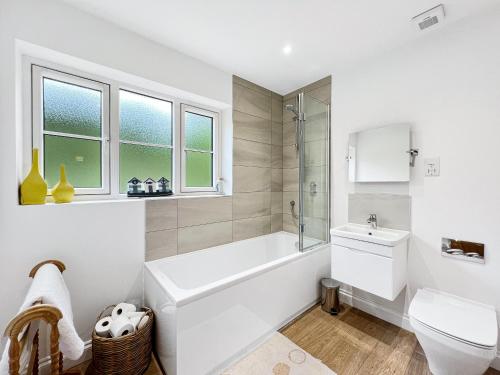 a white bathroom with a tub and a toilet at Meadow View Brushford in Dulverton