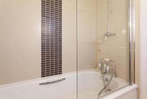 a shower with a glass door and a tub at Luccombe Cottage Luccombe in Luccombe