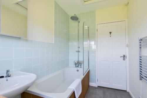 a white bathroom with a tub and a sink at Linhay Cottage Withypool in Withypool