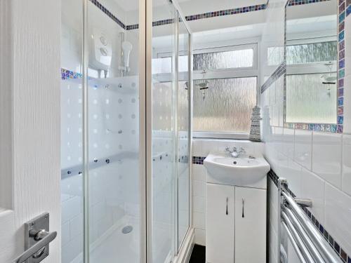 a white bathroom with a shower and a sink at Seagulls Rest Minehead in Minehead