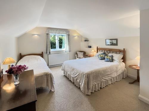 a bedroom with two beds and a window at Forge Cottage Wootton Courtenay in Minehead