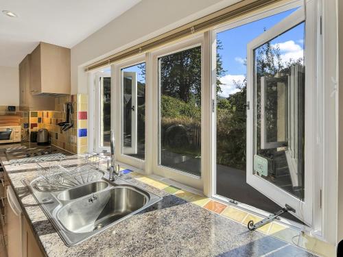 a kitchen with a sink and large windows at Forge Cottage Wootton Courtenay in Minehead