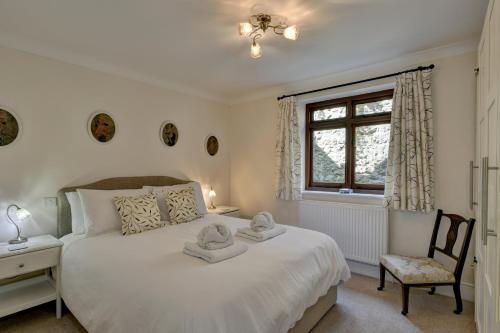 a bedroom with a bed and a chair and a window at Two Grooms Cottage Dunster in Dunster