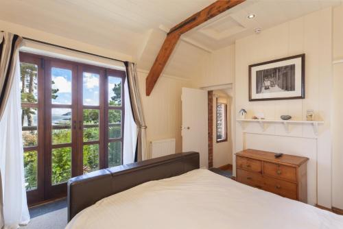 a bedroom with a bed and a large window at The Stable Block Porlock Weir in Porlock