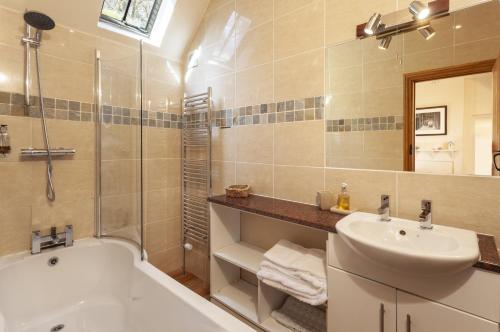a bathroom with a tub and a sink and a shower at The Stable Block Porlock Weir in Porlock