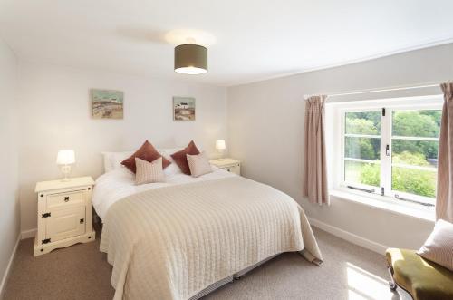 a white bedroom with a bed and a window at Trinity Cottage Roadwater in Nettlecombe