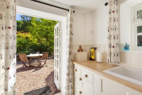 a kitchen with a door open to a patio with a table at Horner Cottage Luccombe in Minehead