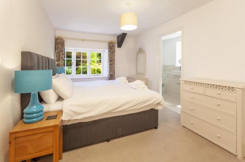 a bedroom with a bed with a blue lamp on a table at Horner Cottage Luccombe in Minehead