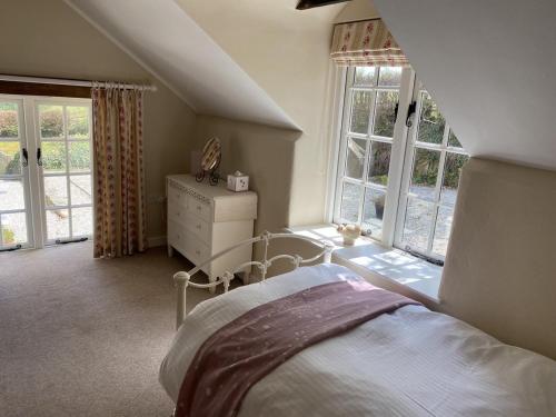 a bedroom with a bed and a dresser and windows at The Piggery Dulverton in Dulverton