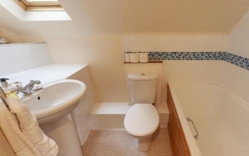 a bathroom with a toilet and a sink and a tub at The Coach House Porlock Weir in Porlock