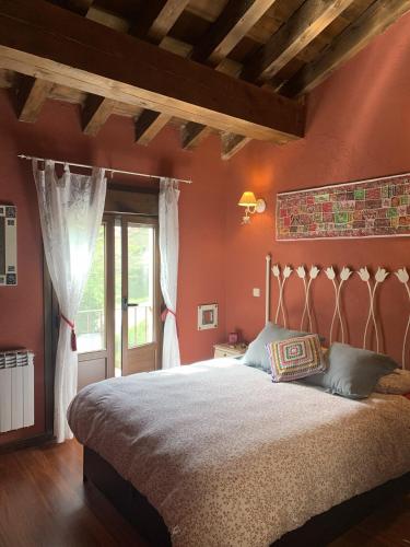 a bedroom with a large bed with red walls at El Acebo de Tanarro in Sepúlveda