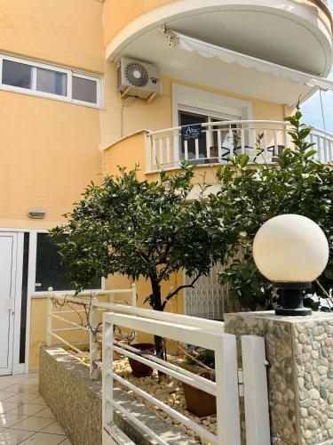 a house with a white fence and a tree at Artemis apartment in Nea Peramos