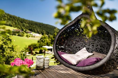 a hanging bed with pillows on a table with flowers at DER MESNERWIRT - 4 Superior - Meraner Land in Avelengo