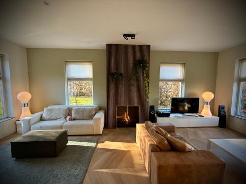 a living room with a couch and a fireplace at Luxe vakantievilla met jacuzzi in Zeewolde